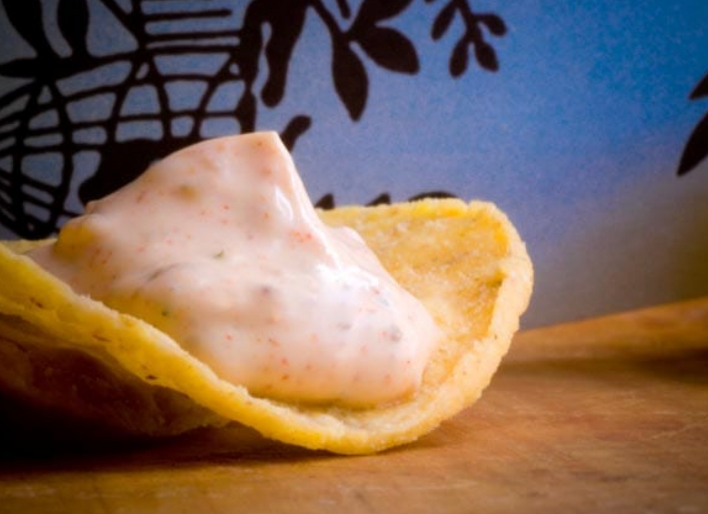 Tortilla chip with creamy dip on a wooden surface