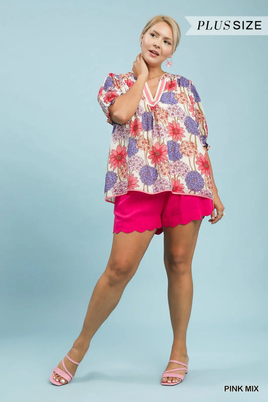 Woman wearing a colorful blouse and pink shorts on a light blue background
