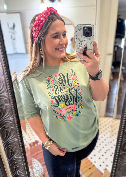 Woman taking a mirror selfie wearing a light green t-shirt with floral text design.