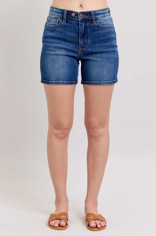Blue denim shorts worn by a person on a plain background