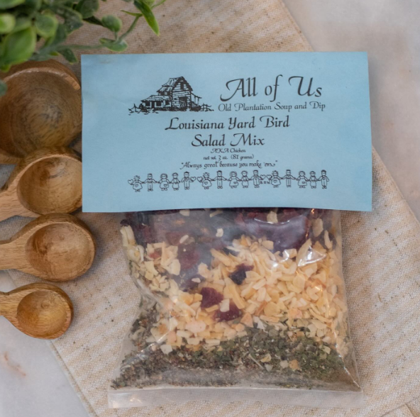 Packaged salad mix with a label for 'All of Us' on a rustic background with wooden spoons.