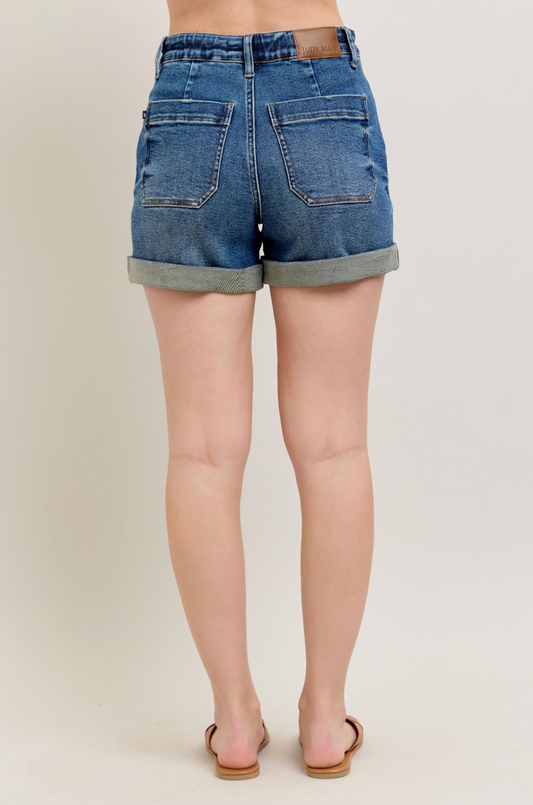 Denim shorts worn by a person on a plain background