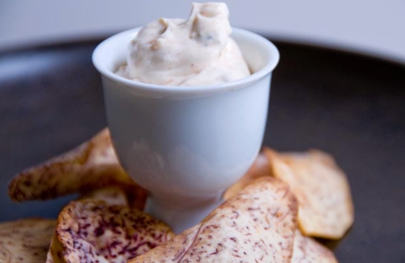 White bowl of cream cheese spread with crackers on a dark surface