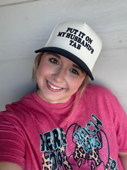 Person wearing a white cap with text and a pink shirt with graphic design.