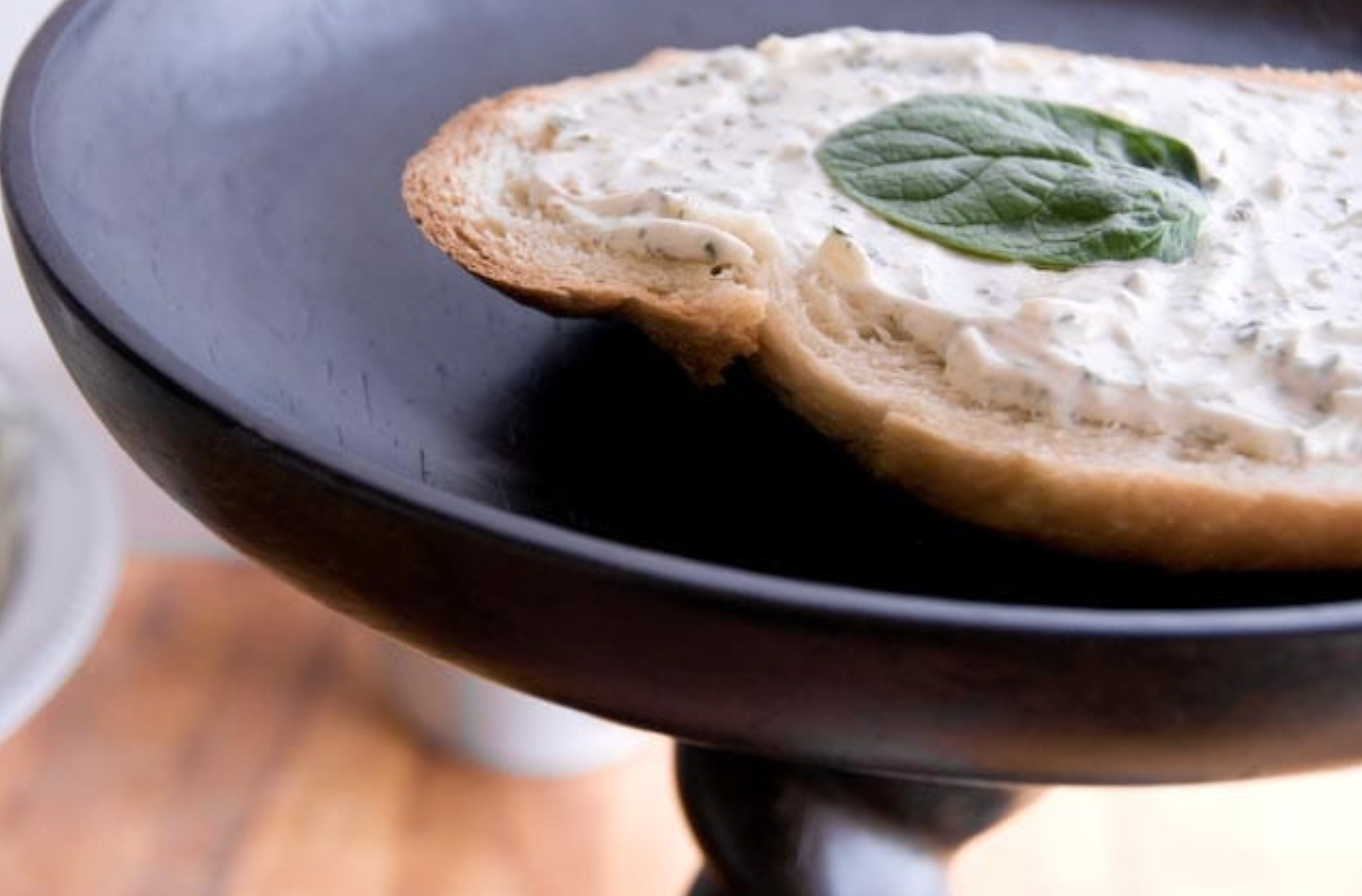 Bread with spread and basil leaves on a black plate