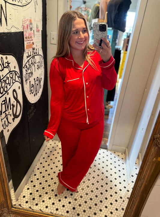 Person wearing red pajamas taking a mirror selfie in a room with a decorative wall.