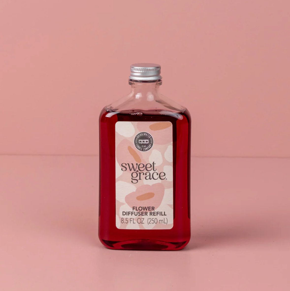 Bottle of 'sweet grace' flower diffuser refill on a pink background
