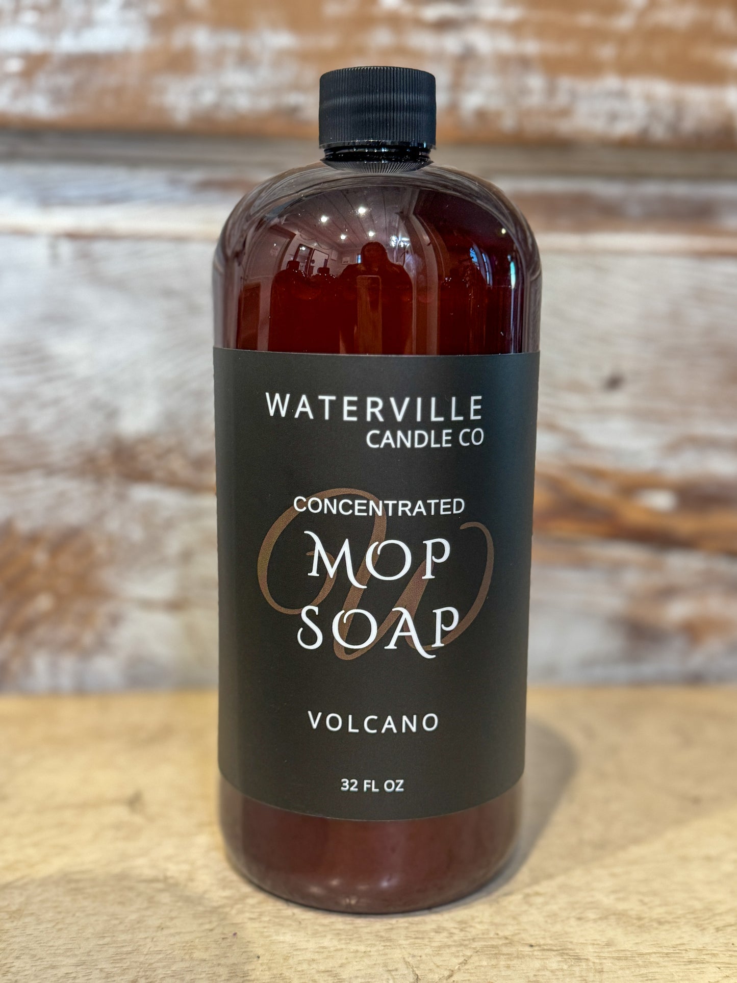 Bottle of Waterville Candle Co. Mop Soap on a wooden surface with a rustic background