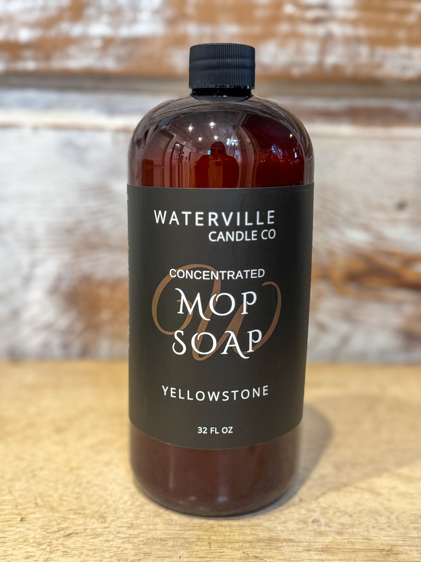 Bottle of concentrated mop soap from Waterville Candle Co on a wooden surface.