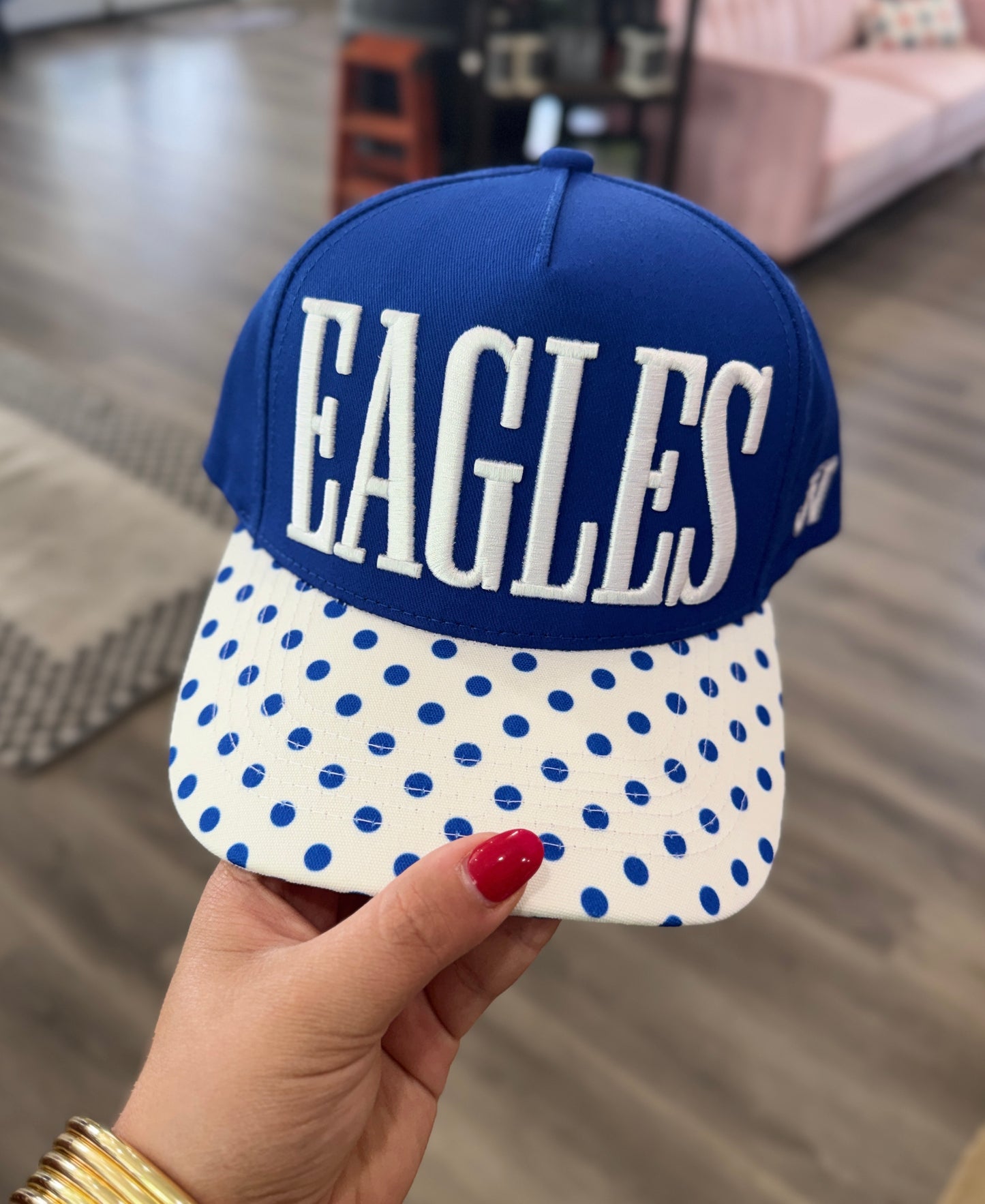 Blue and white polka dot cap with 'EAGLES' text held by a hand.