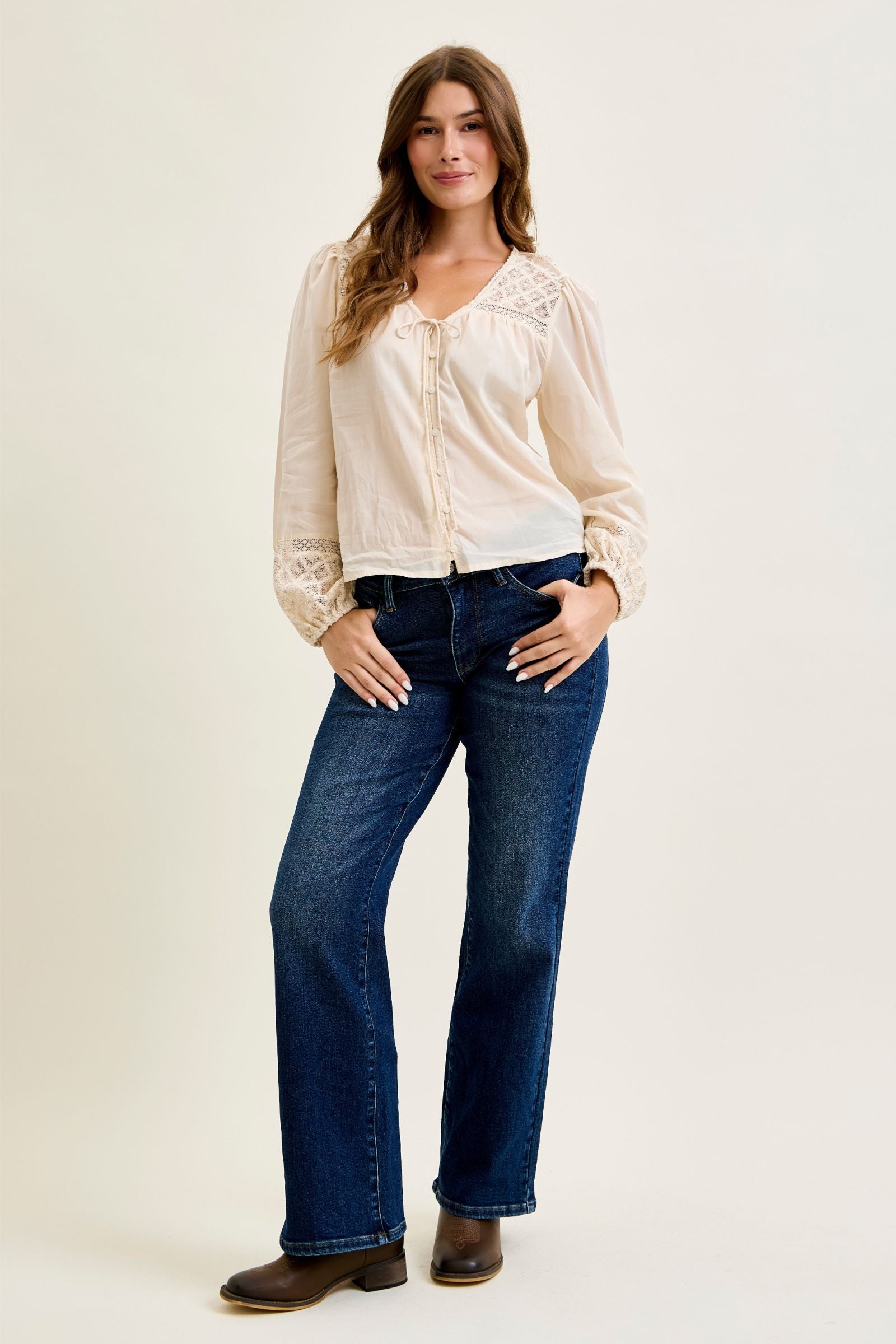 Woman wearing a white blouse and blue jeans on a plain background