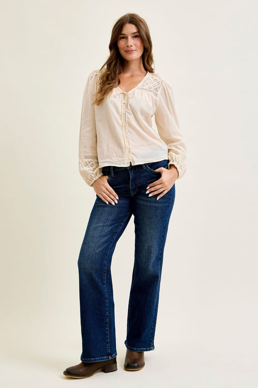 Woman wearing a white blouse and blue jeans on a plain background