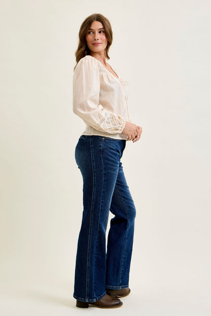 Woman wearing a white blouse and blue jeans on a plain background