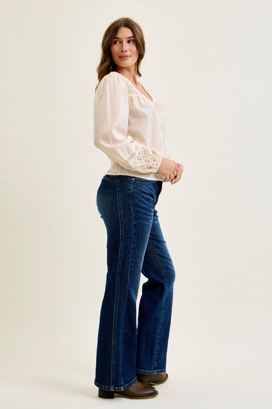 Woman wearing a white blouse and blue jeans on a plain background
