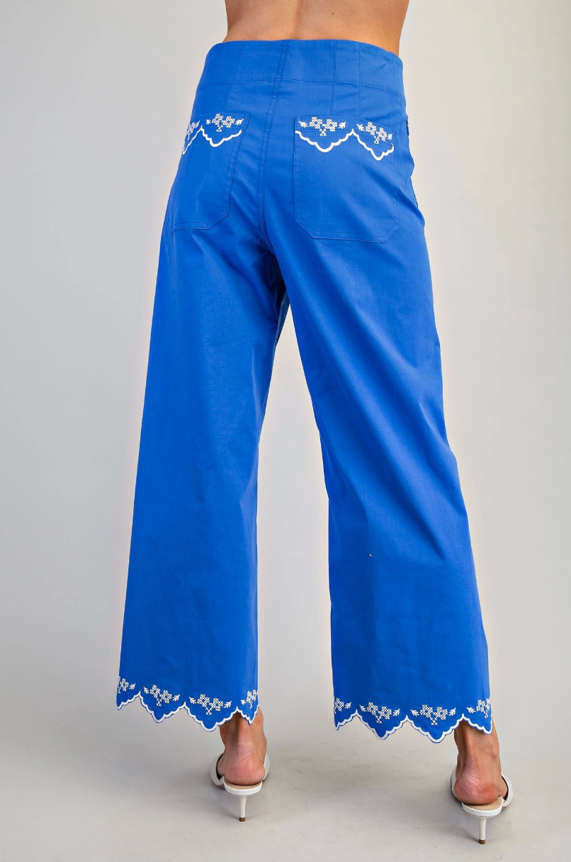 Blue pants with white lace detailing on a plain background