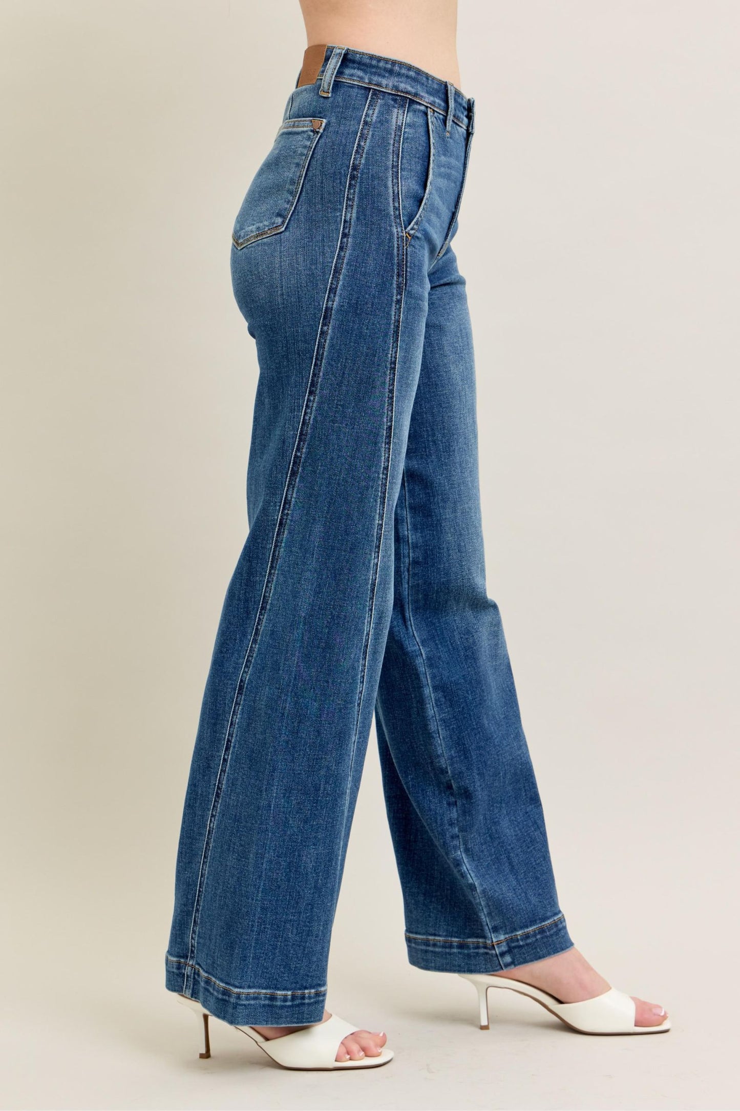 Blue jeans worn by a person on a beige background