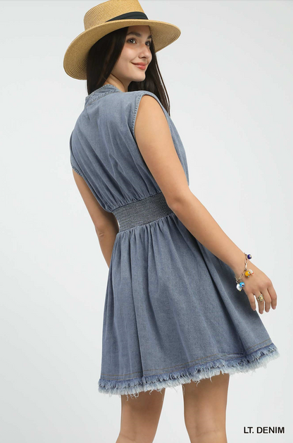 Woman wearing a light denim dress and straw hat on a white background