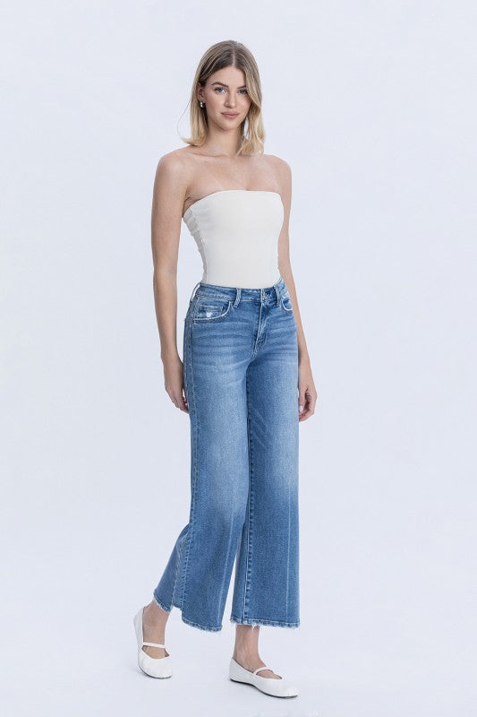 Woman wearing a white strapless top and blue jeans on a white background