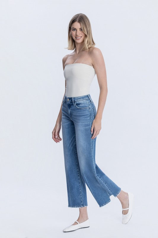 Woman wearing a white strapless top and blue jeans on a white background