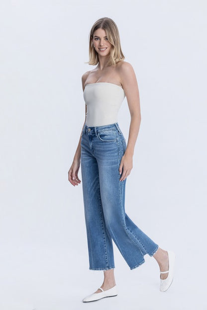 Woman wearing a white strapless top and blue jeans on a white background