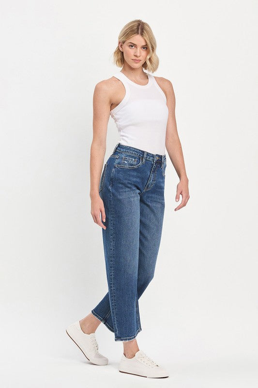Woman wearing a white tank top and blue jeans on a white background