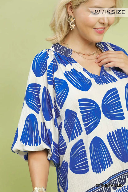Woman wearing a blue and white patterned blouse against a green background