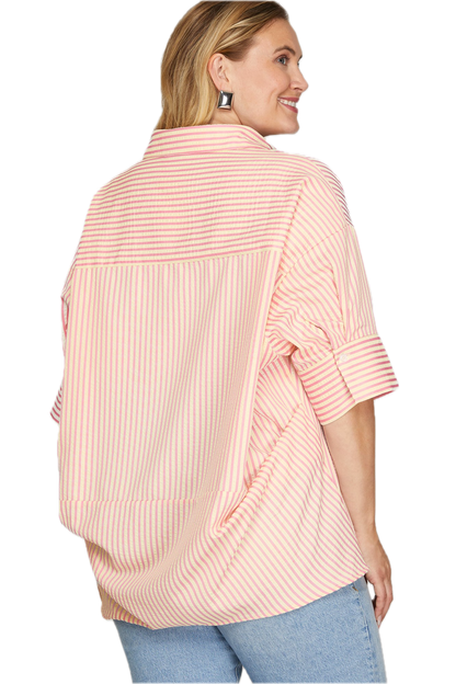 Woman wearing a pink striped shirt with rolled-up sleeves on a white background