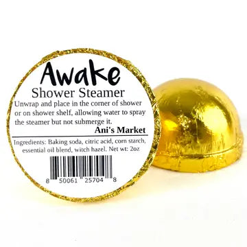 A gold foil-wrapped shower steamer shown open, with the inside label reading 'Awake Shower Steamer' and 'Ani's Market' on a white background.