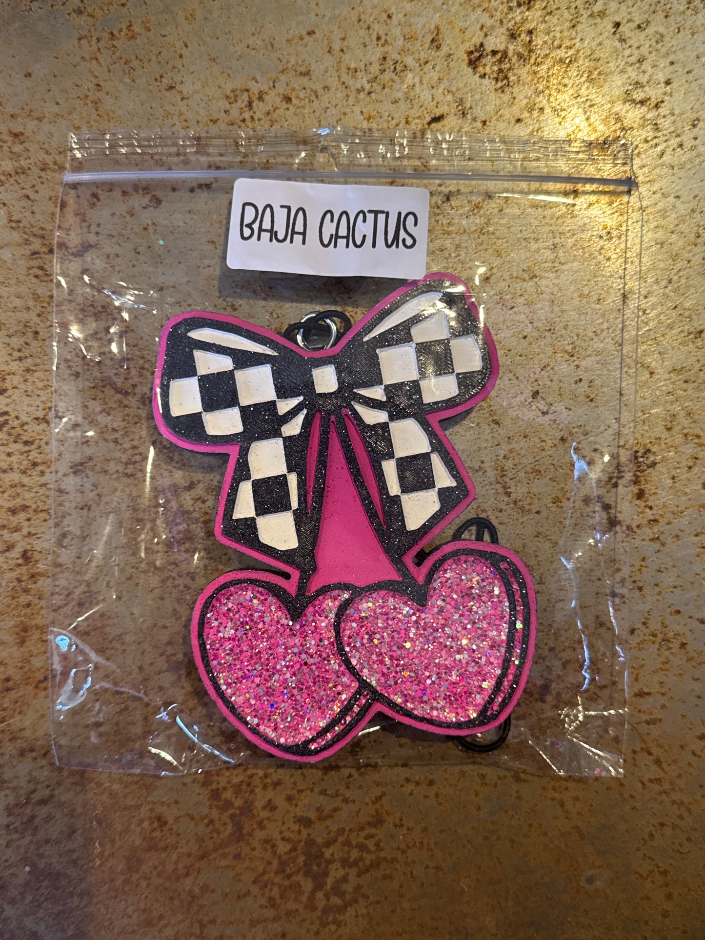 Pink and black checkered butterfly patch in clear packaging on a textured surface