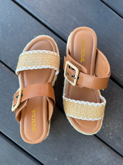 Pair of brown sandals with jute straps on a wooden surface