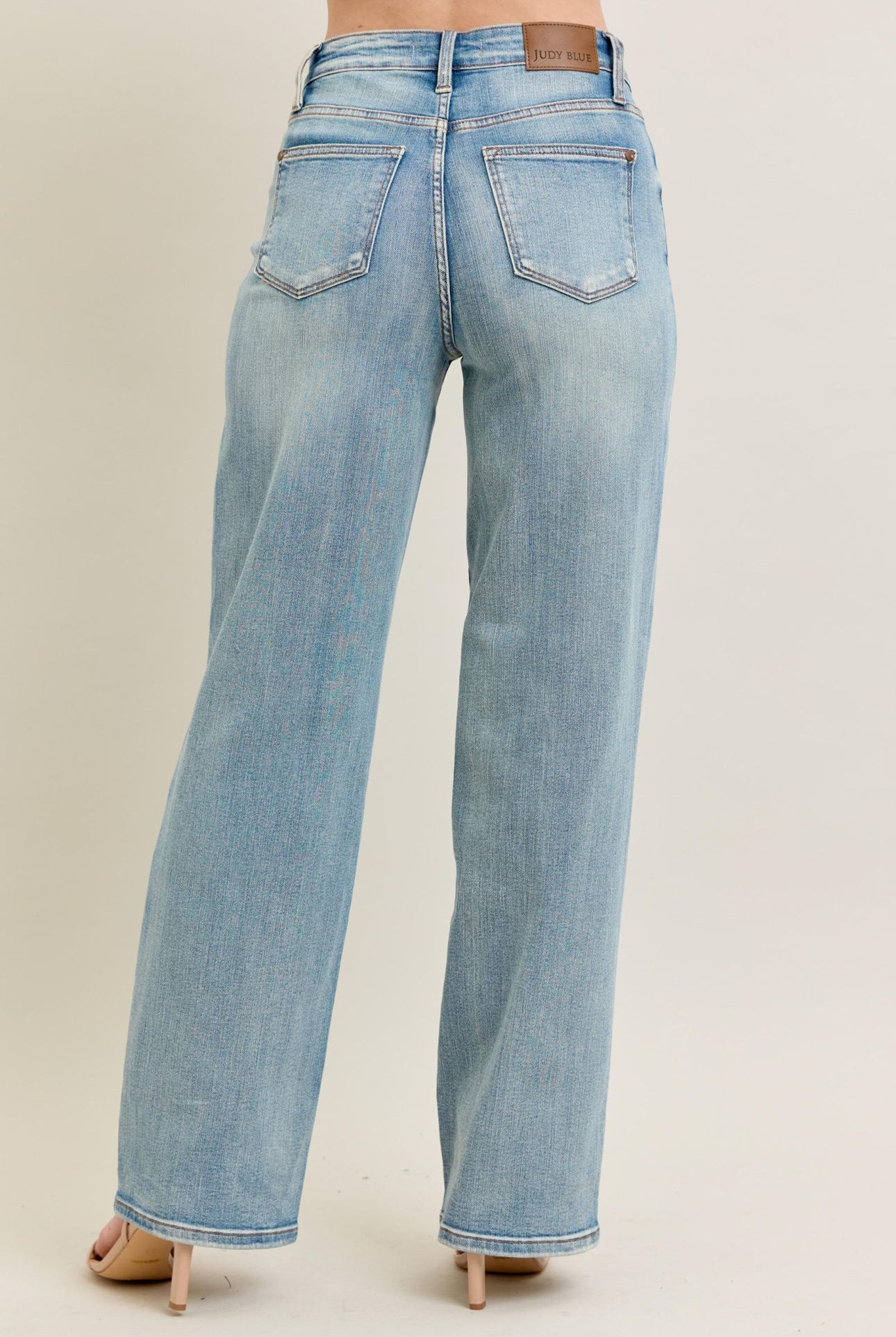 Light blue jeans worn by a person on a beige background
