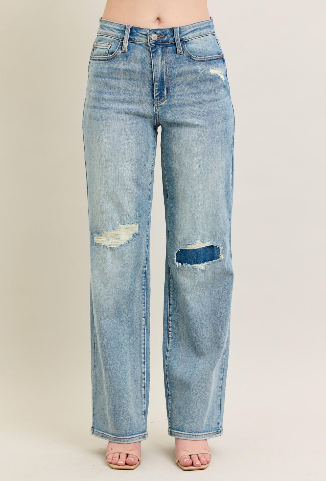Light blue jeans with distressing on a beige background