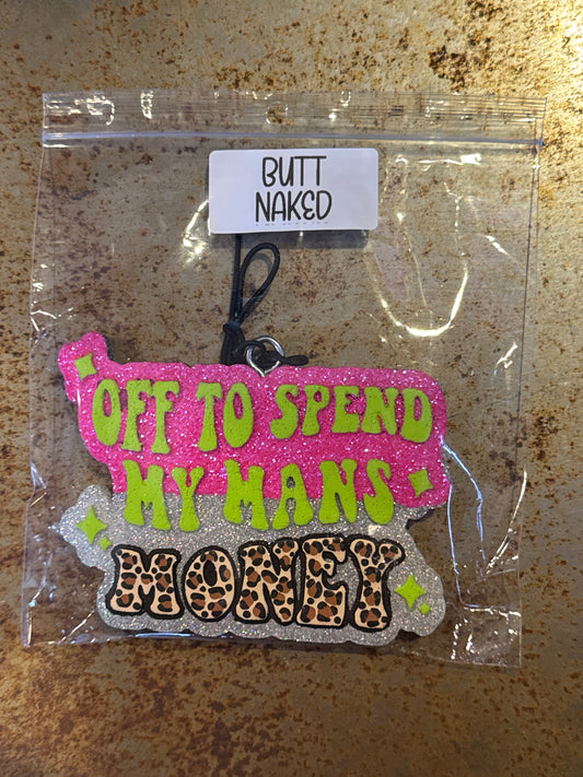 Keychain with text and leopard print design in clear packaging on a rusty surface