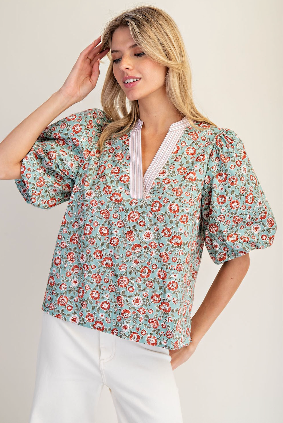 Woman wearing a floral blouse with puff sleeves against a plain background