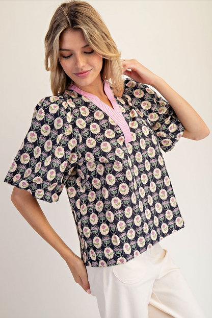 Woman wearing a floral patterned blouse with a pink collar against a white background