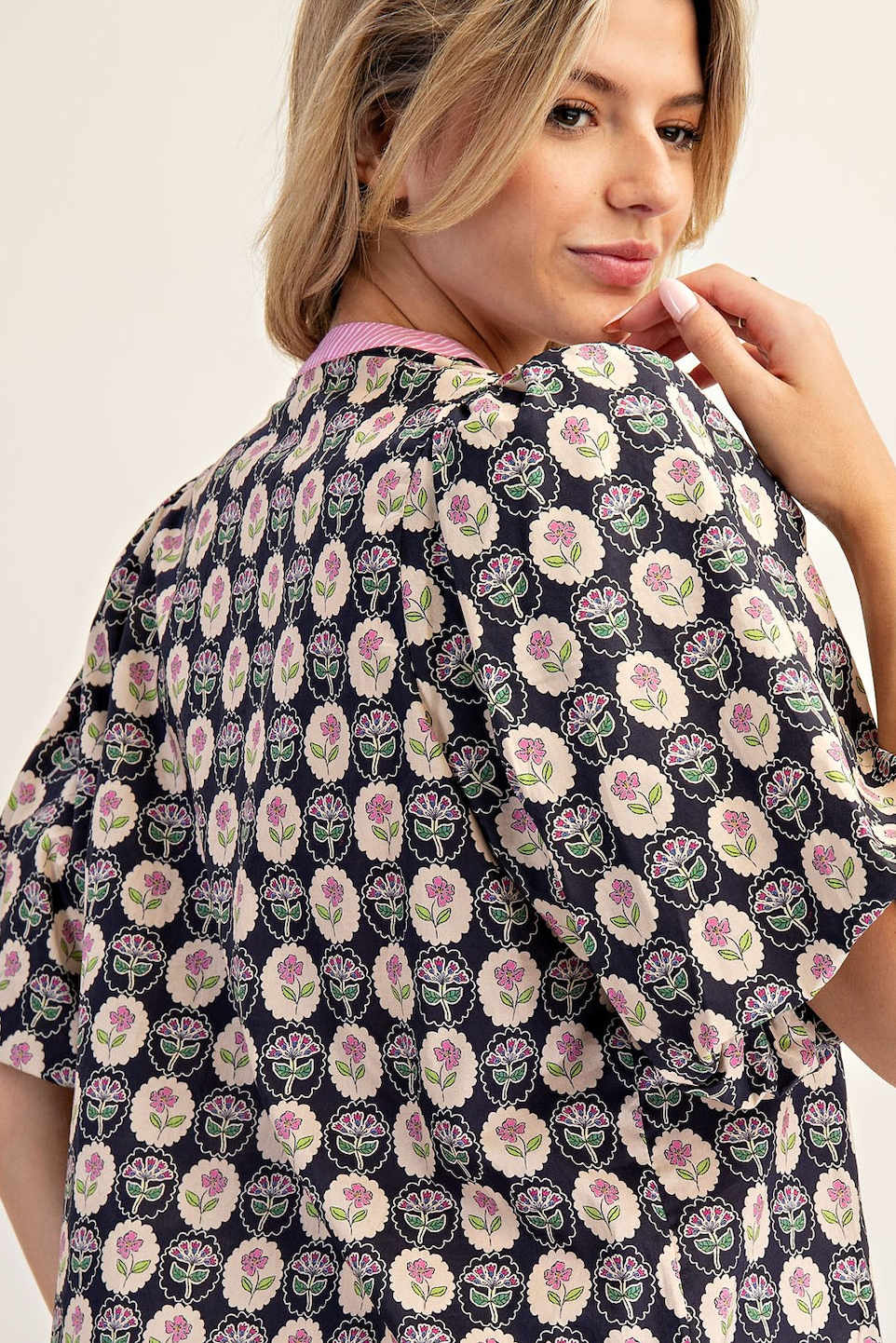Woman wearing a floral patterned shirt against a plain background