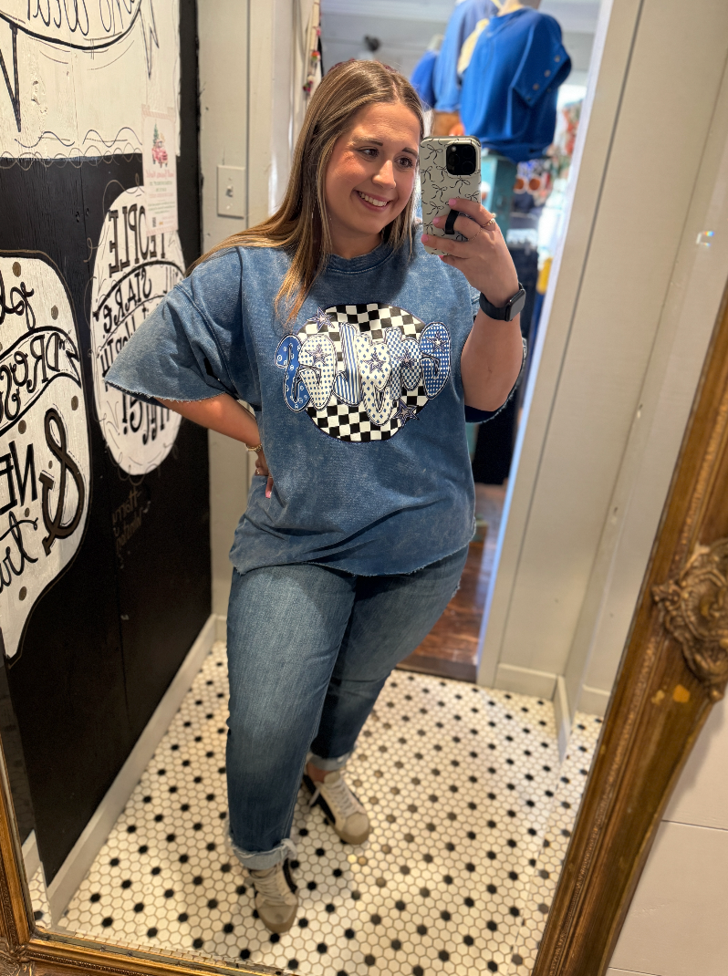 Woman taking a mirror selfie wearing a blue graphic t-shirt and jeans in a room with decorative elements.