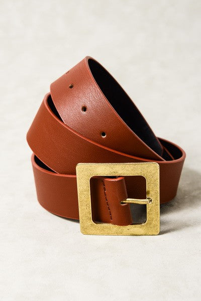 Brown leather belt with a gold buckle on a light background