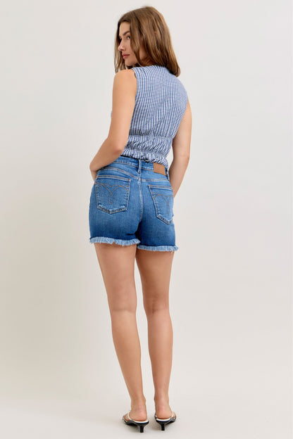 Woman wearing a blue checkered top and denim shorts on a white background