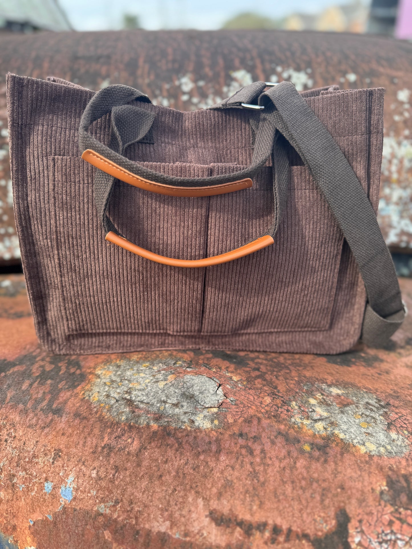 Brown corduroy bag with camel accents on a textured surface