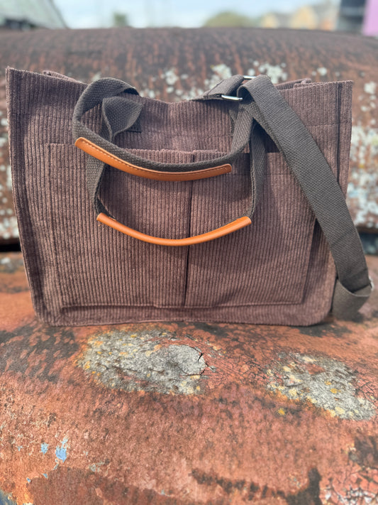Brown corduroy bag with camel accents on a textured surface