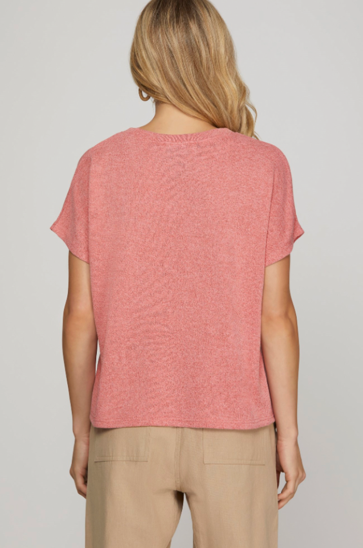 Person wearing a pink t-shirt and beige pants on a plain background