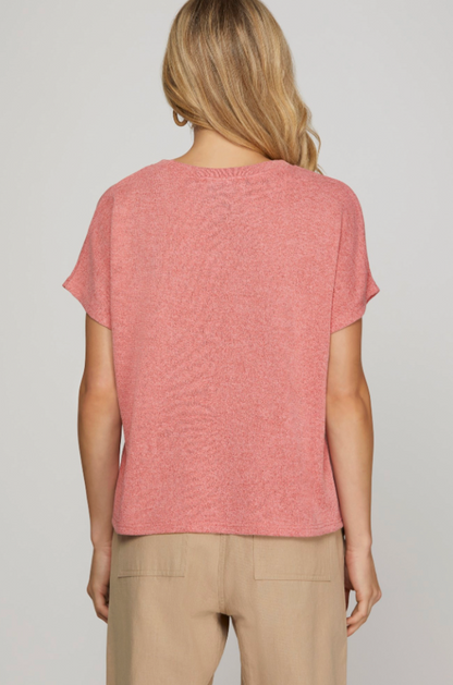 Person wearing a pink t-shirt and beige pants on a plain background