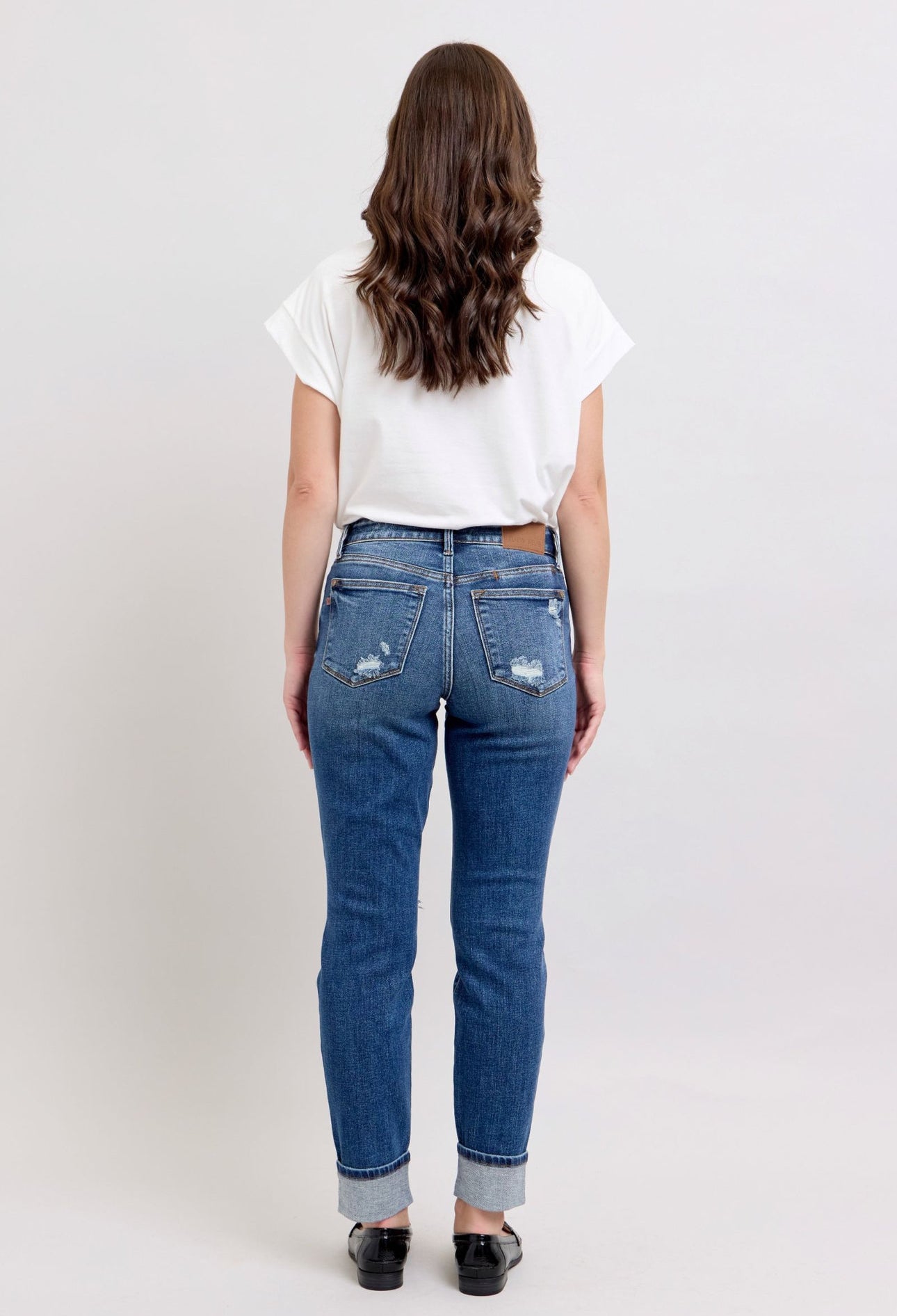 Person wearing blue jeans and a white t-shirt on a plain background