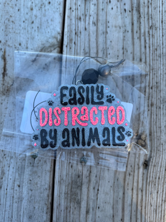 Tag with 'Easily Distracted by Animals' text on a wooden surface
