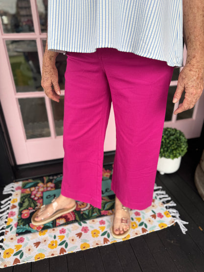 Person wearing bright pink pants and a white shirt on a floral rug.