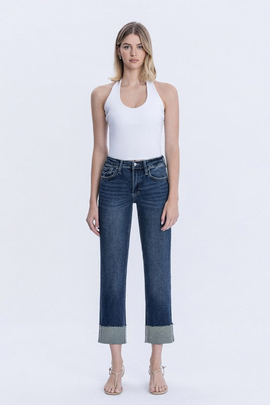 Woman wearing a white tank top and blue jeans on a white background