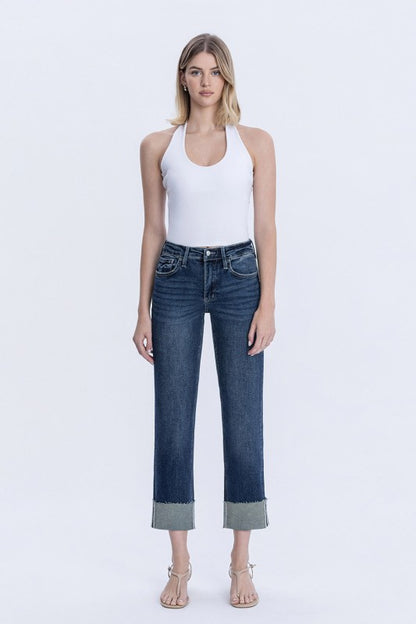 Woman wearing a white tank top and blue jeans on a white background