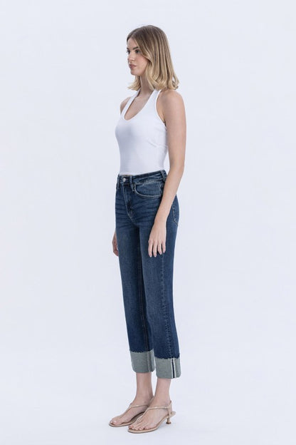 Woman wearing a white tank top and blue jeans on a white background