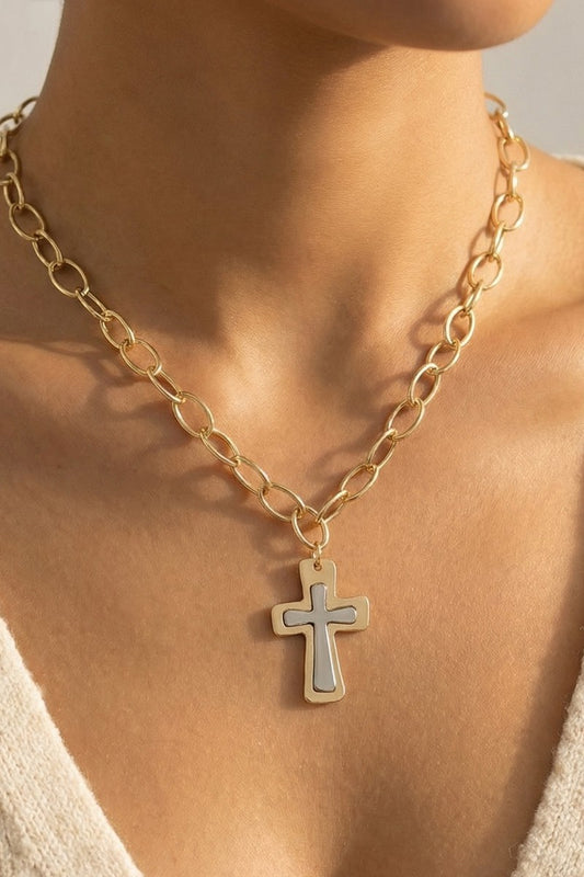 Gold chain necklace with a cross pendant on a person's neck